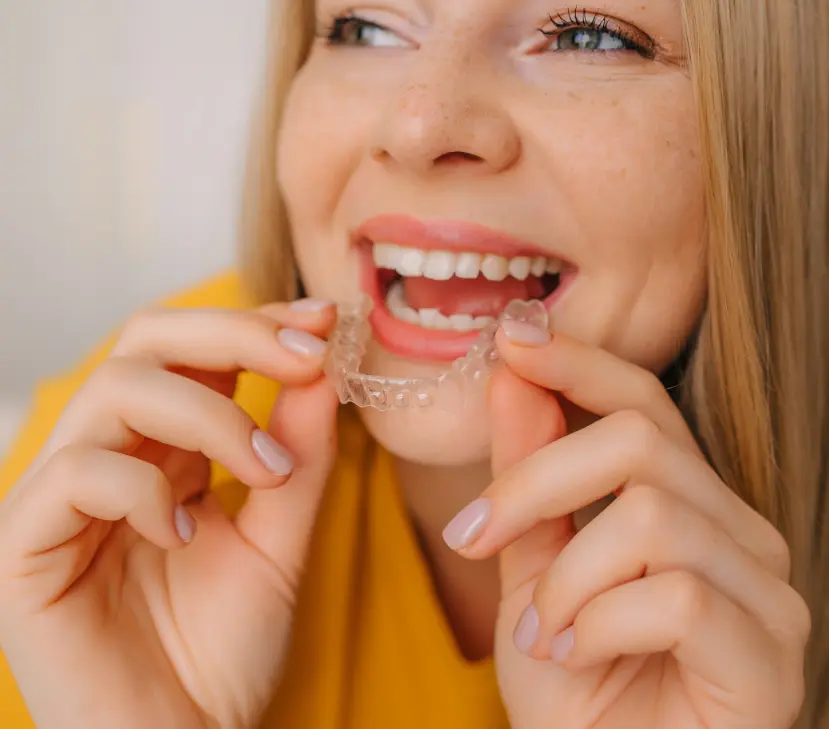 smiling woman inserting clear aligner