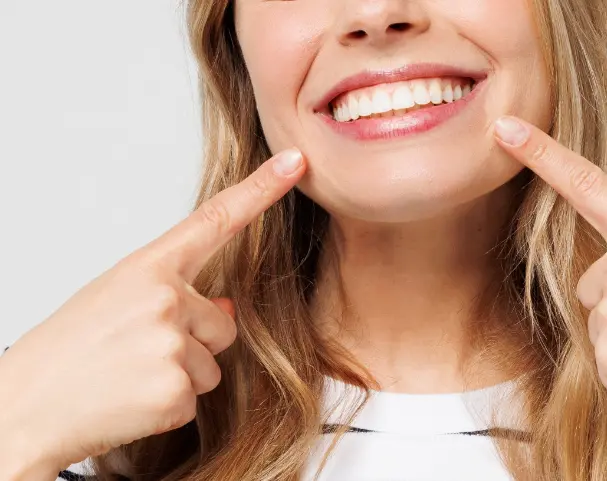 woman smiling pointing at her teeth